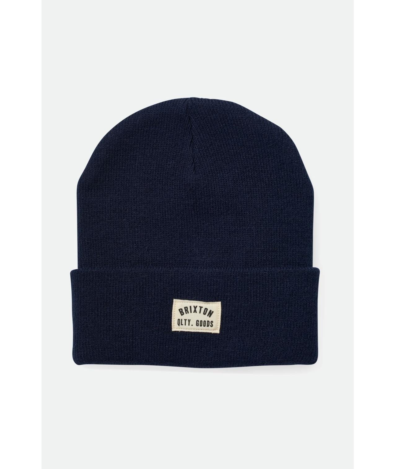 Navy blue beanie with a logo patch on a light gray background